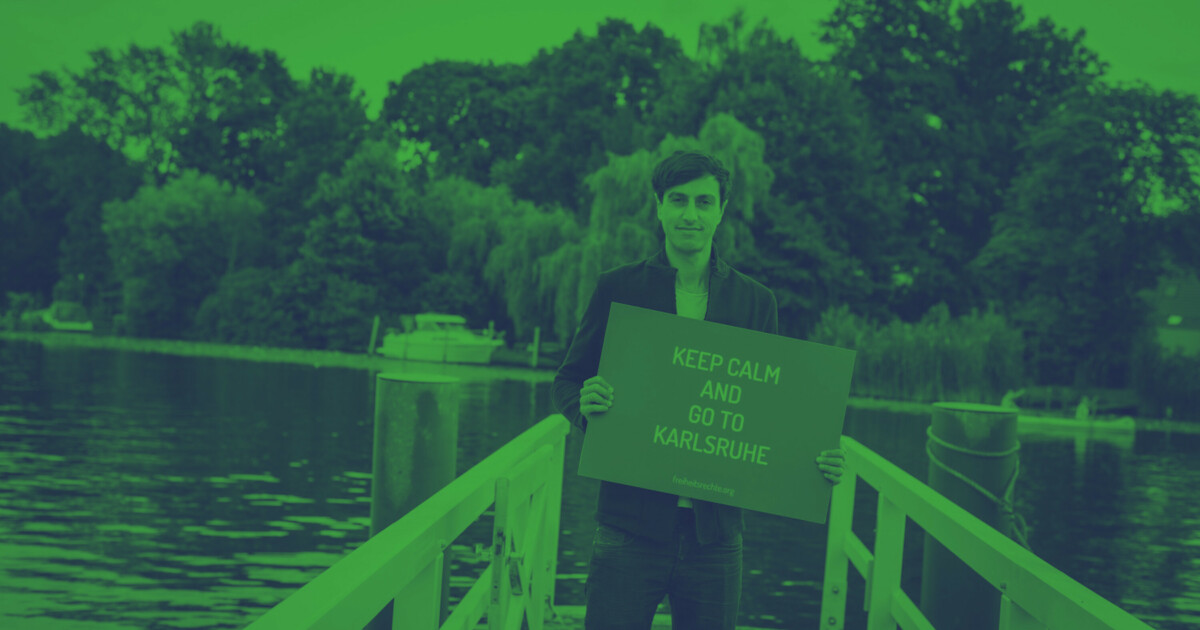 Bijan Moini hält ein Schild mit dem Schriftzug "Keep calm and go to Karlsruhe"